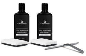 Two bottles of Glassguard Glass Restoration Stain Remover with sponges and a grey squeegee