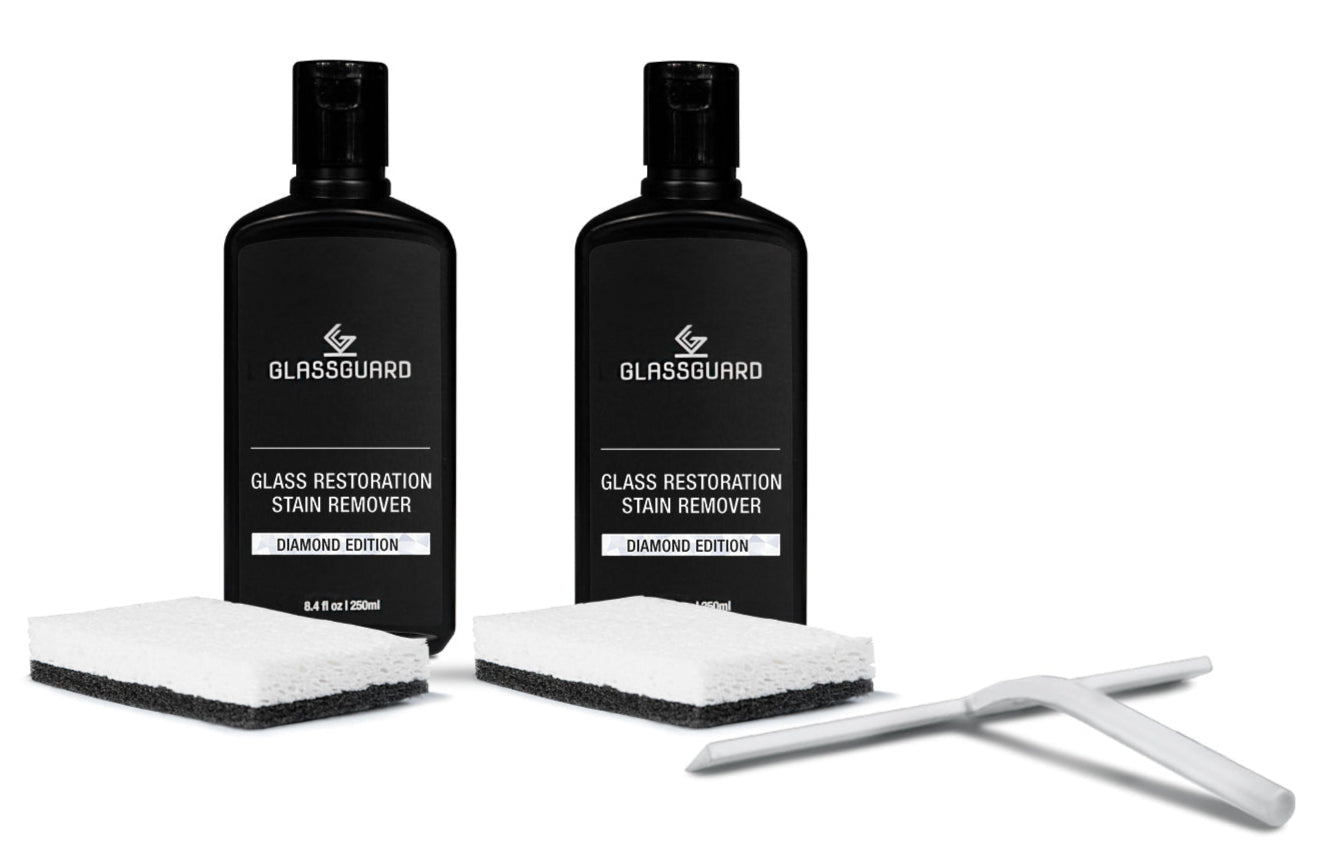 Two bottles of Glassguard Glass Restoration Stain Remover with sponges and a white squeegee
